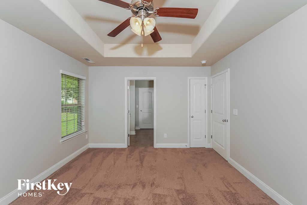 a bedroom with a ceiling fan and a door to a hallway