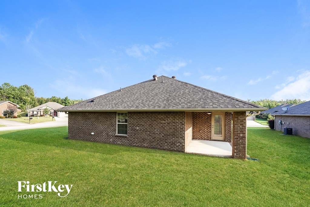 a small brick house with a porch on a grass field