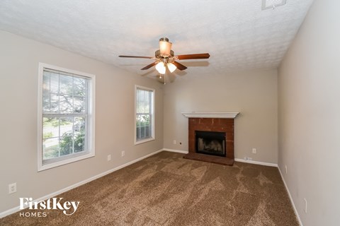 the living room has a fireplace and a ceiling fan
