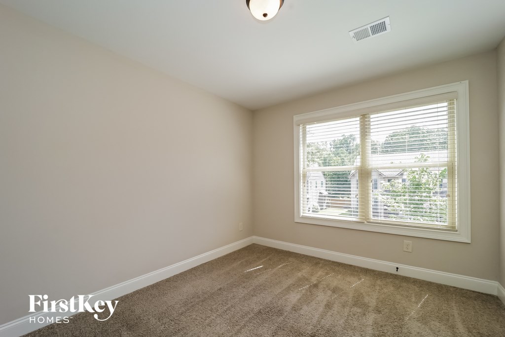a bedroom with a large window and a carpeted floor