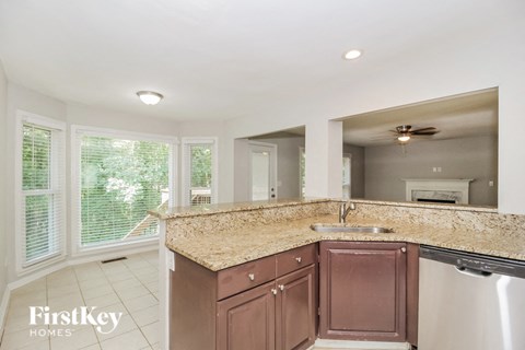 A kitchen with a granite countertop and a stainless steel dishwasher.