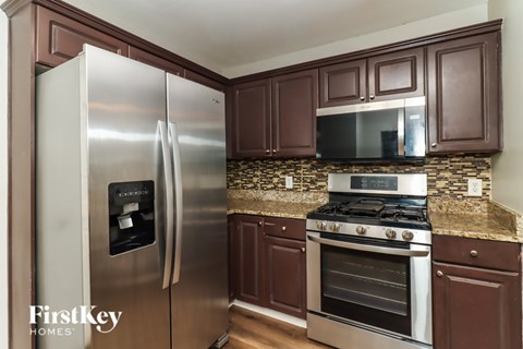 A kitchen with a stainless steel refrigerator and a stove top oven.