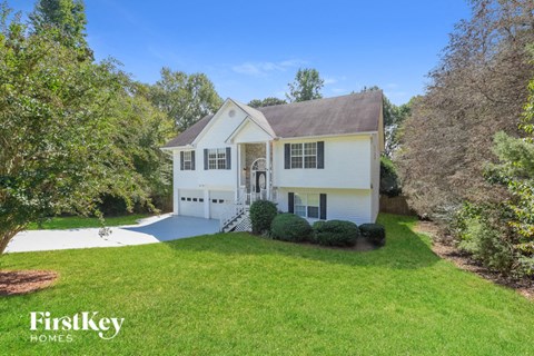 a white house with a green lawn and a driveway