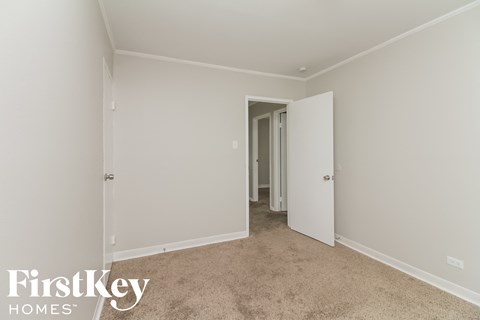a bedroom with white walls and carpet and a door to a closet
