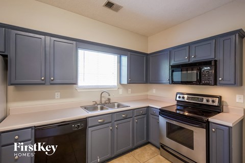 A kitchen with dark blue cabinets and a stove top oven.