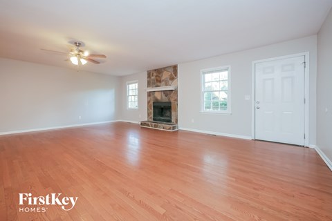an empty living room with a fireplace and wood flooring