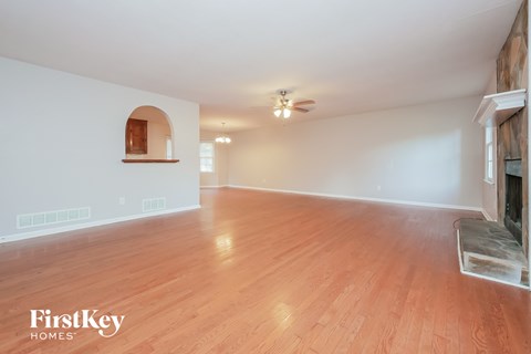 an empty living room with a fireplace and wood flooring