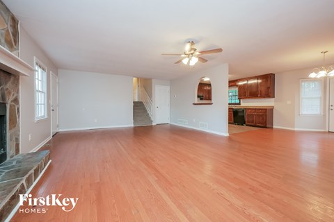 an empty living room with wood flooring and a ceiling fan