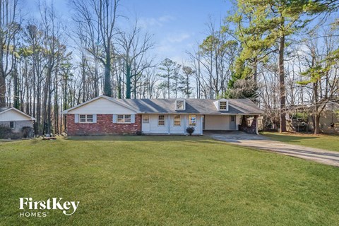 A house with a lawn in front of it and trees in the background.