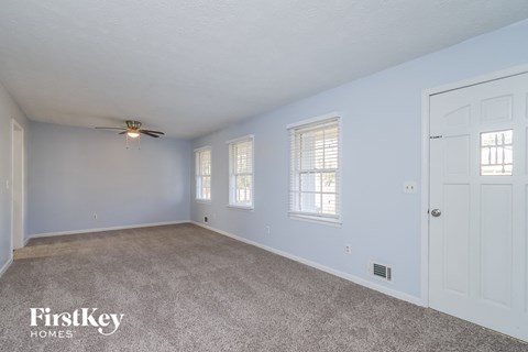 A spacious room with a ceiling fan and two windows.