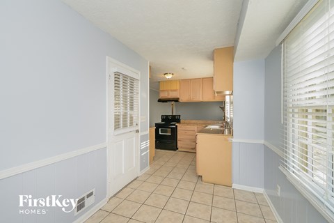 A kitchen with a white door and a black stove top oven.