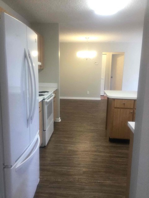 A kitchen with a white refrigerator and wooden cabinets.
