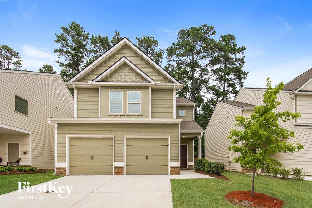 a tan house with two garage doors and a tree