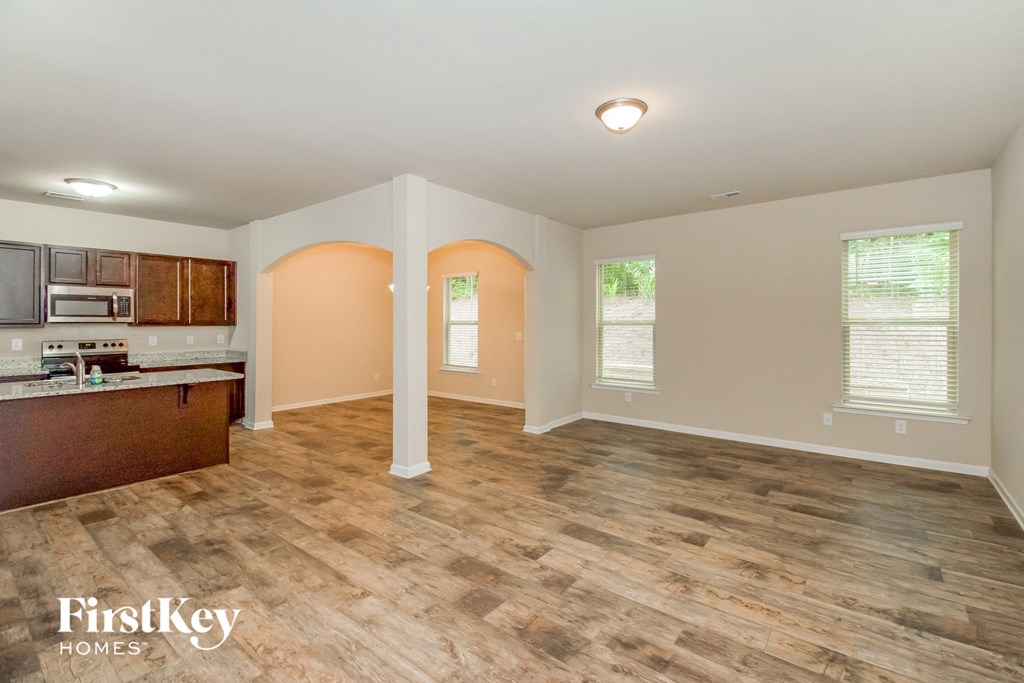 the living room and kitchen of an empty house with wood flooring