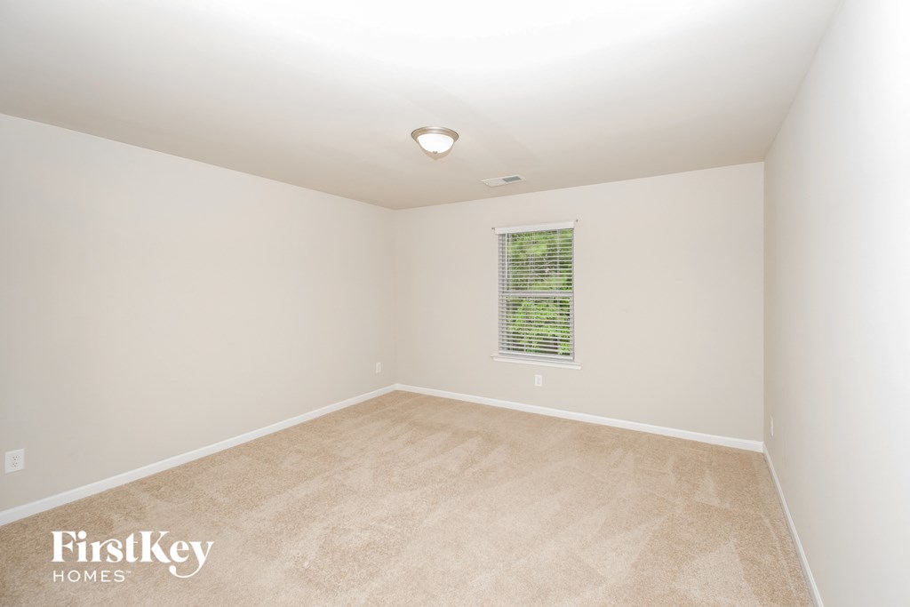a bedroom with white walls and carpet and a window