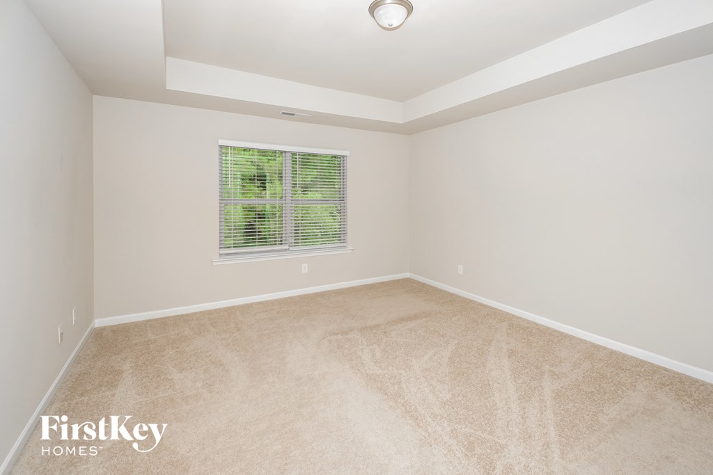 a spacious living room with carpet and a window
