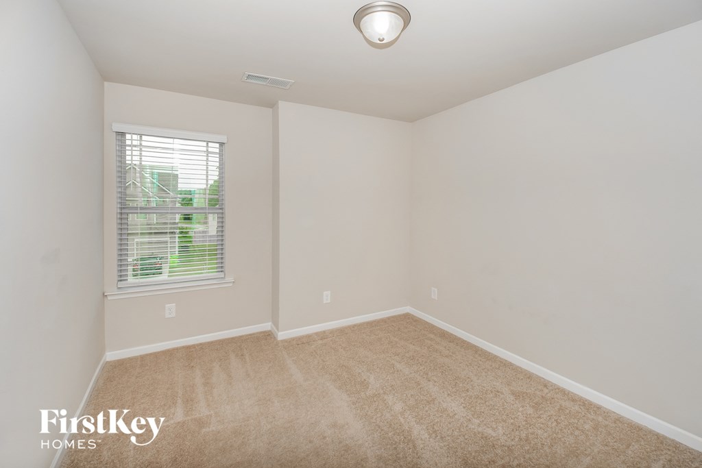 a spacious room with carpet and a window