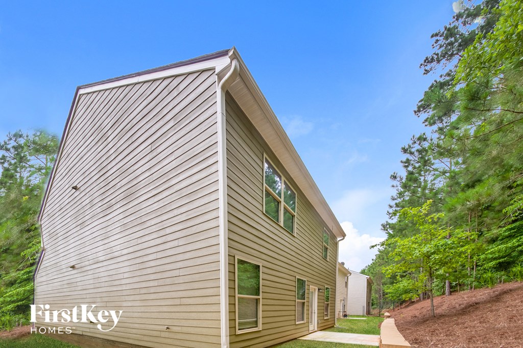the view of the side of a house with trees and a sidewalk
