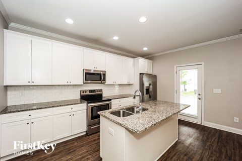 A kitchen with white cabinets and a granite countertop.