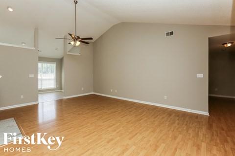 A spacious room with wooden flooring and a ceiling fan.