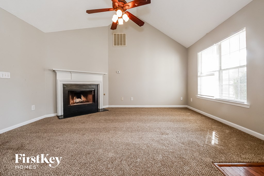 an empty living room with a fireplace and a ceiling fan