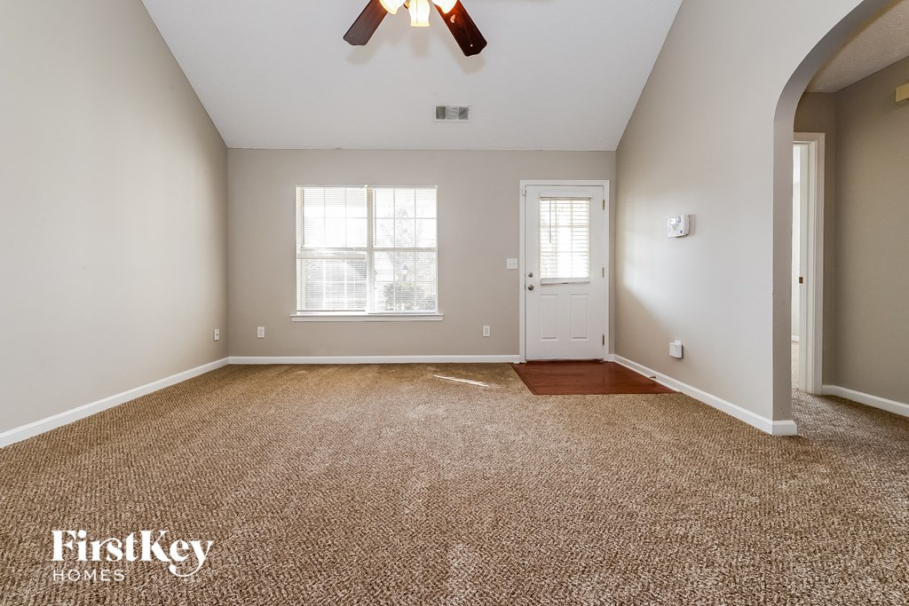 an empty living room with carpet and a white door