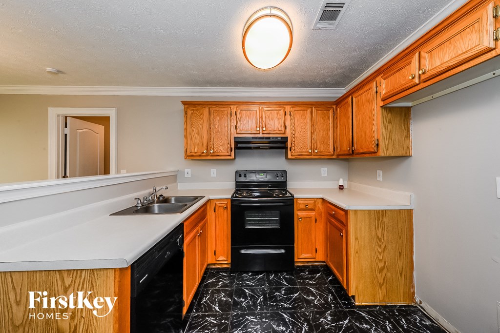a kitchen with wood cabinets and black appliances and white counter tops