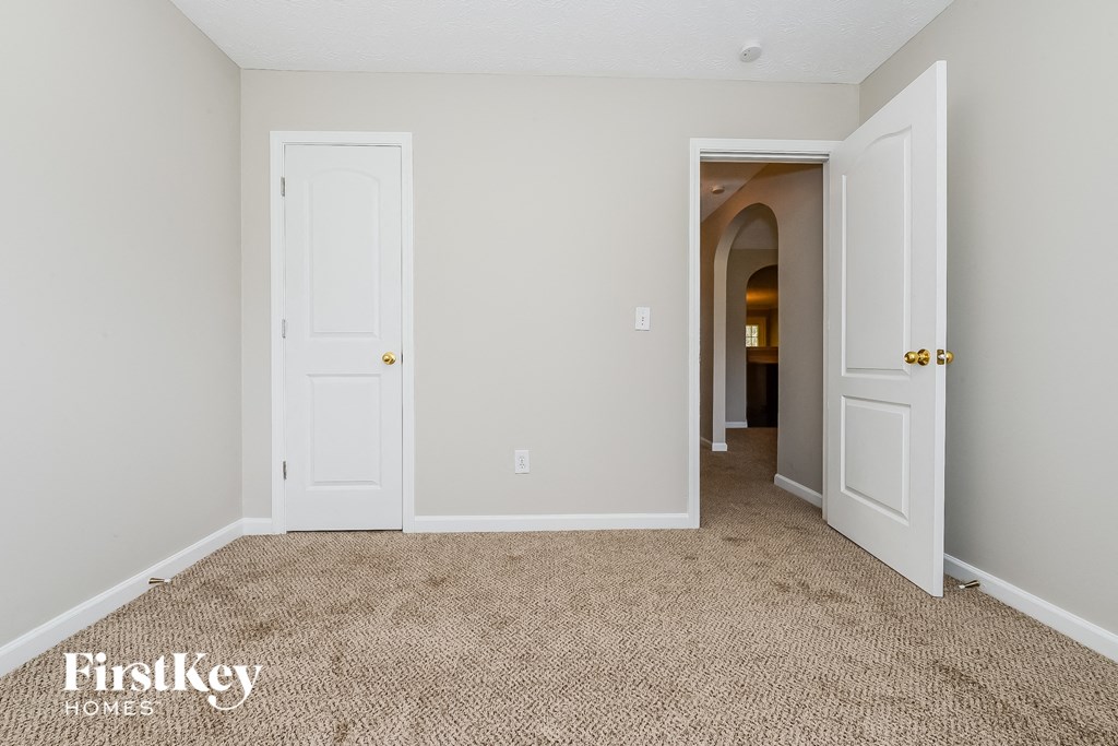 a bedroom with two doors and a carpeted floor    and a hallway