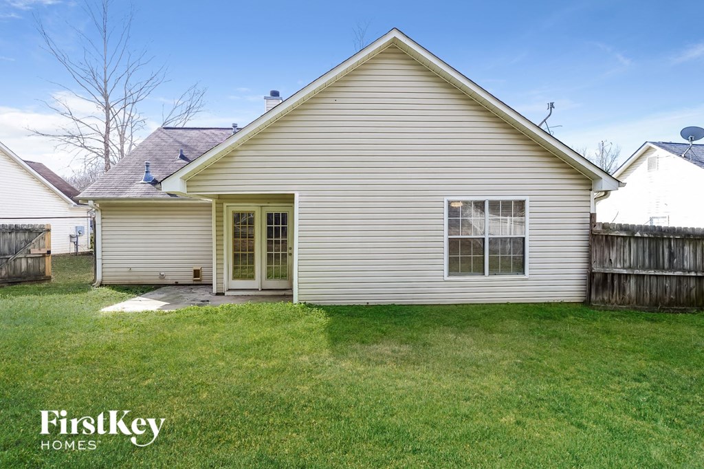 the outside of a white house with a yard and a backdoor