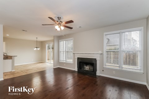 A spacious living room with a fireplace and a ceiling fan.