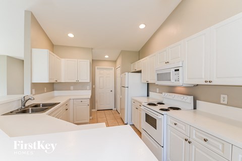 A kitchen with white cabinets and appliances.