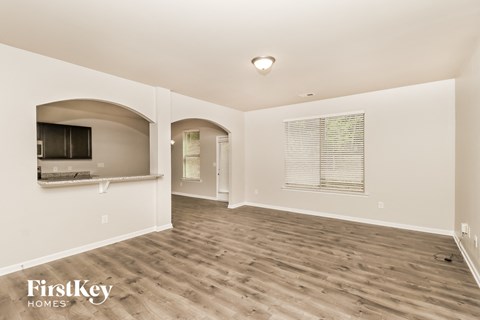 a living room with hardwood floors and a kitchen with a tv