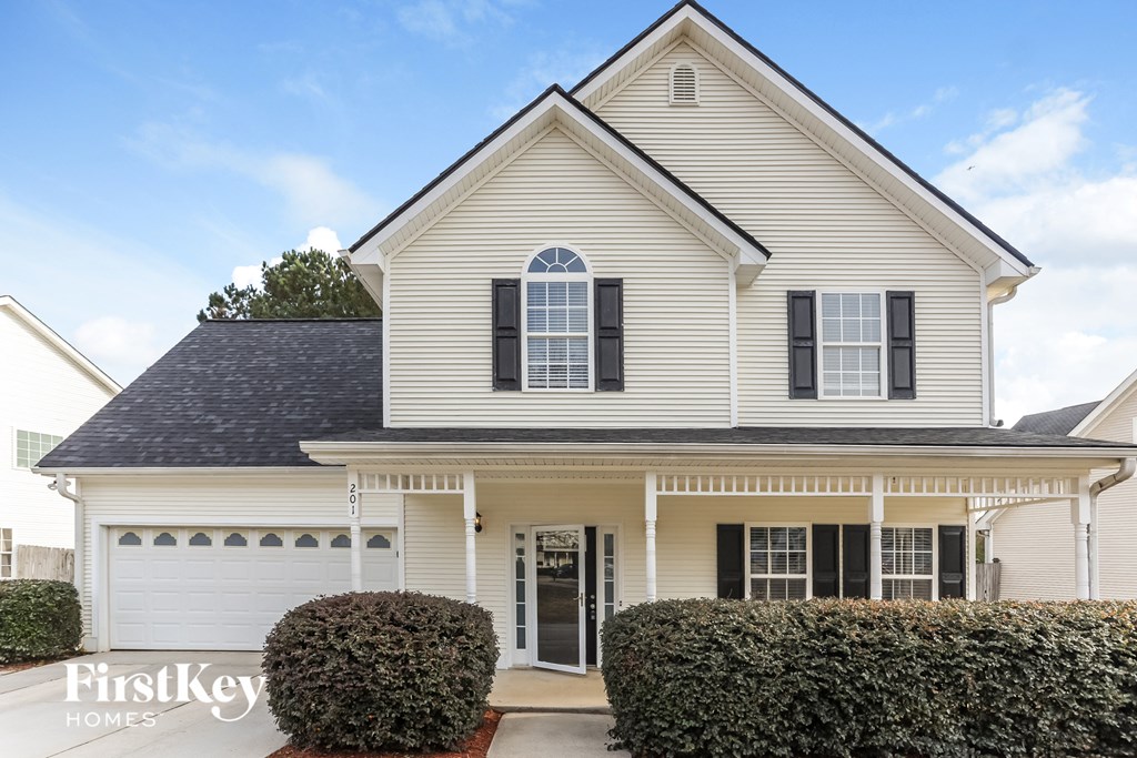 a white house with black shutters and a white driveway