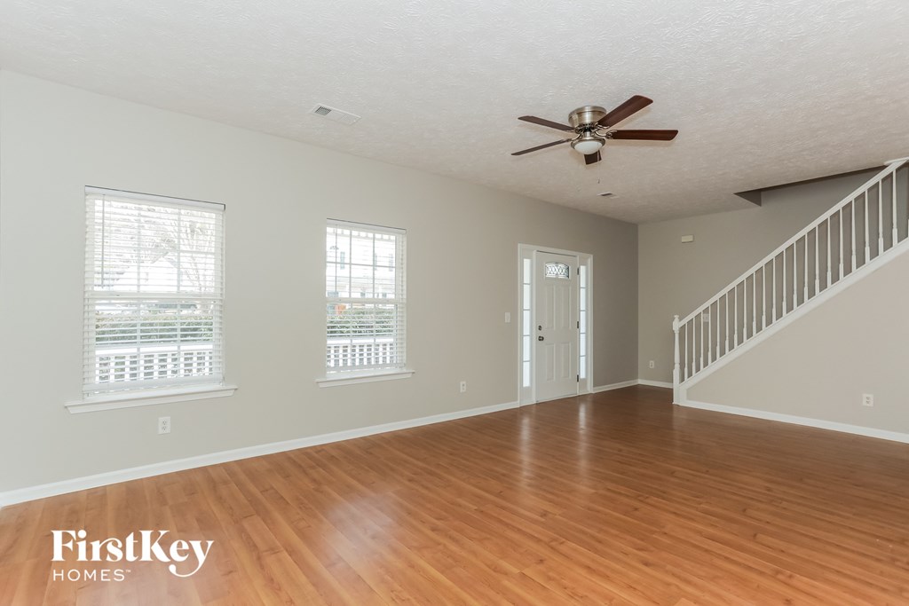 an empty living room with wood floors and a ceiling fan