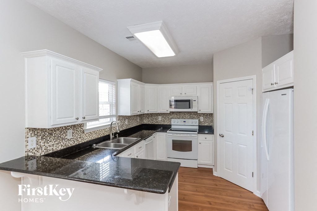 a white kitchen with granite counter tops and white cabinets