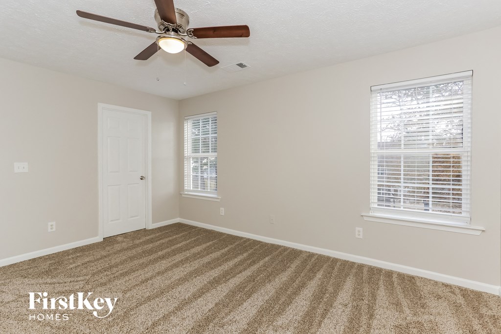 the living room is spacious and clean with a ceiling fan
