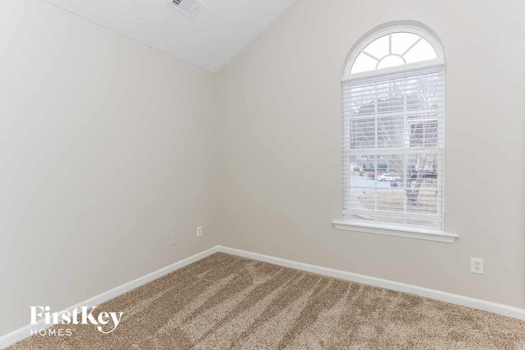 a bedroom with a window and a carpeted floor