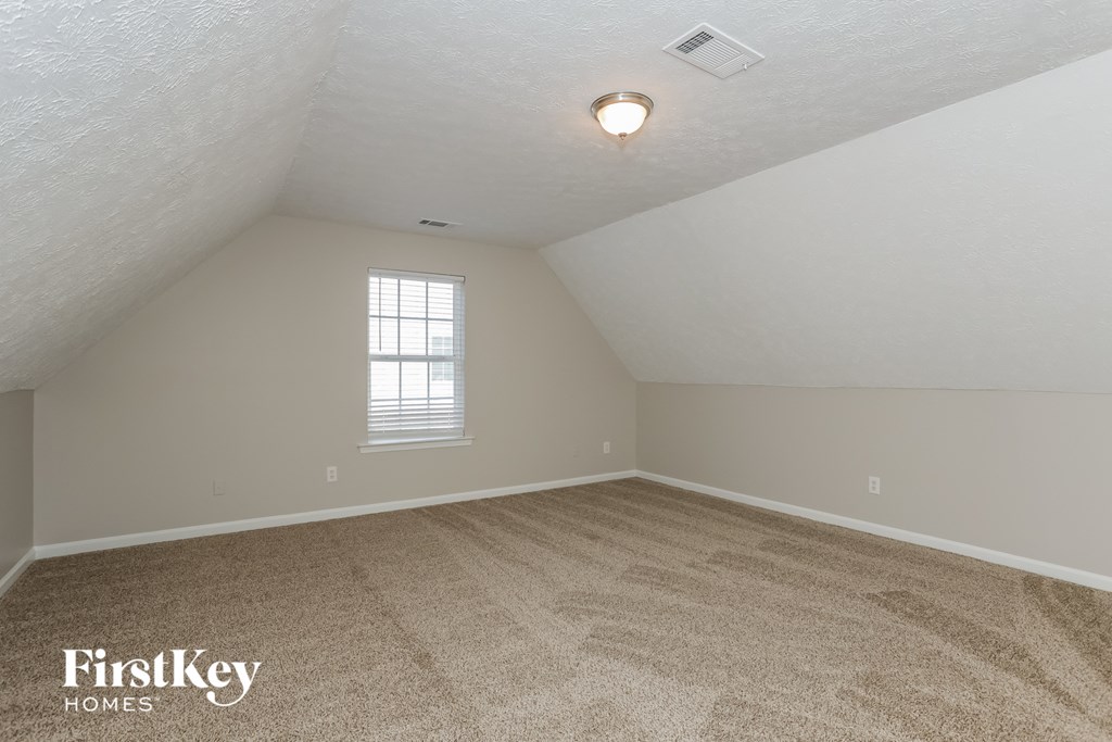 the bedroom of an attic with carpet and a window