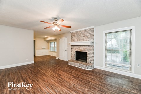 A spacious living room with a fireplace and a ceiling fan.
