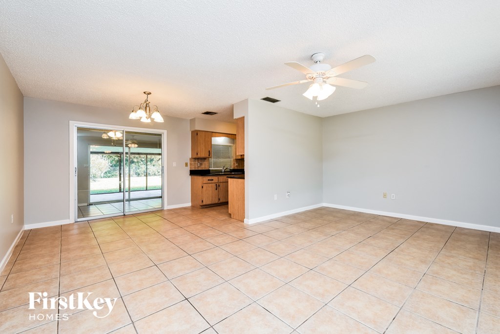 an empty living room and kitchen with a ceiling fan