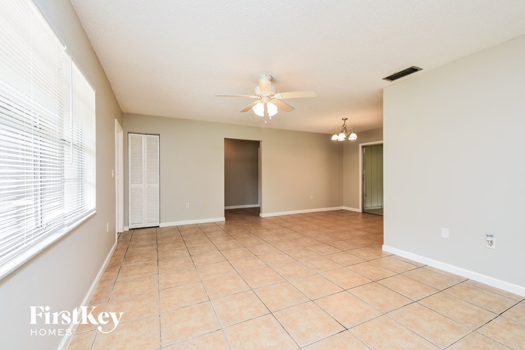 an empty living room with a ceiling fan and a large window