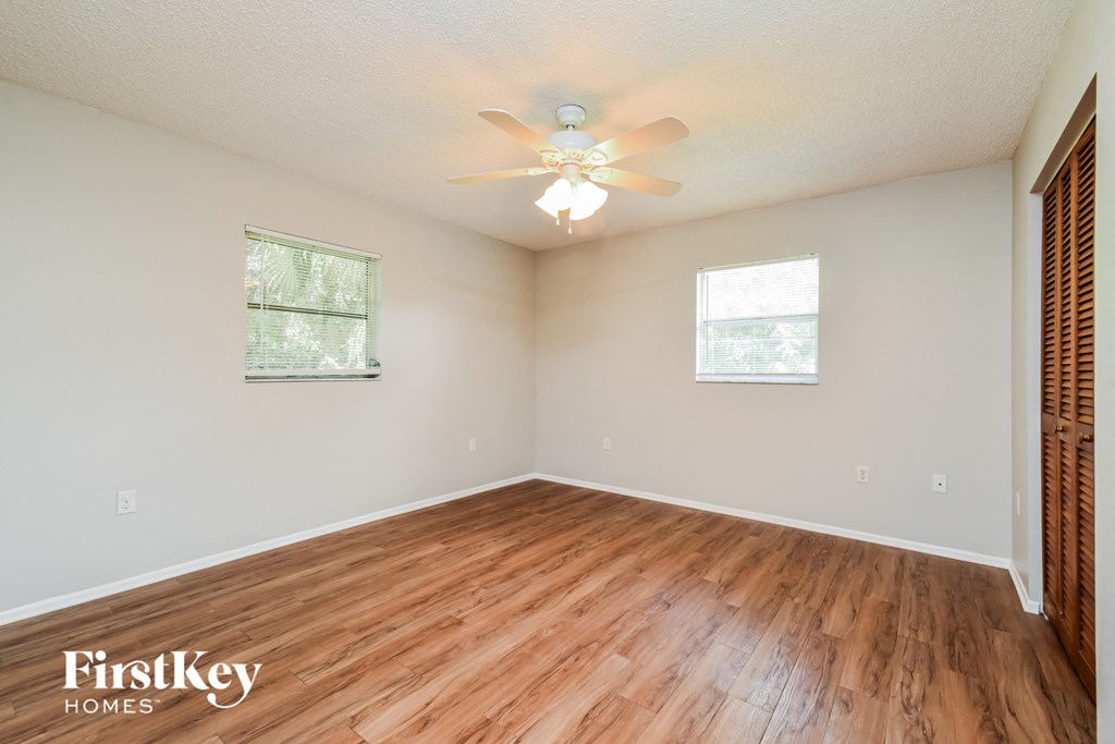 an empty living room with wood floors and a ceiling fan