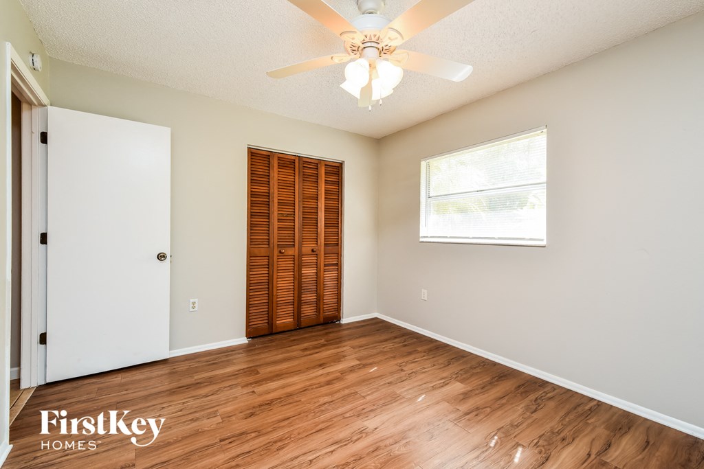 a bedroom with hardwood flooring and a ceiling fan