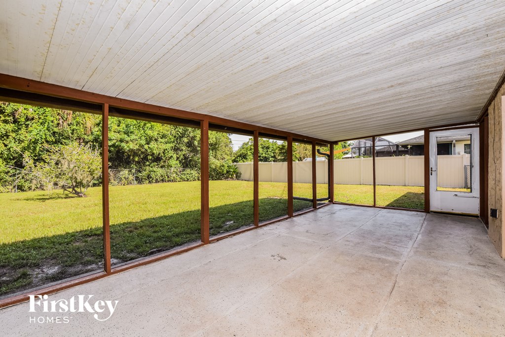 a covered patio with a lawn in the back of a house