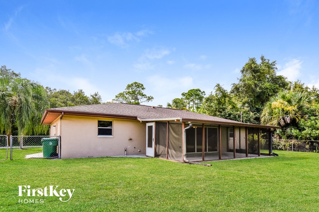 a small tan house with a yard and a fence