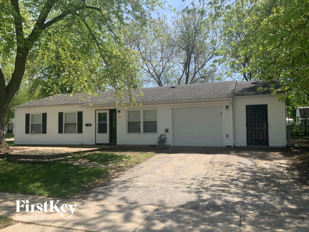 a white house with a driveway and trees