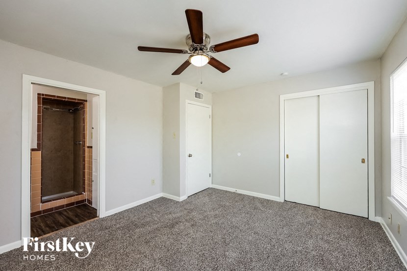 an empty bedroom with a ceiling fan and white walls