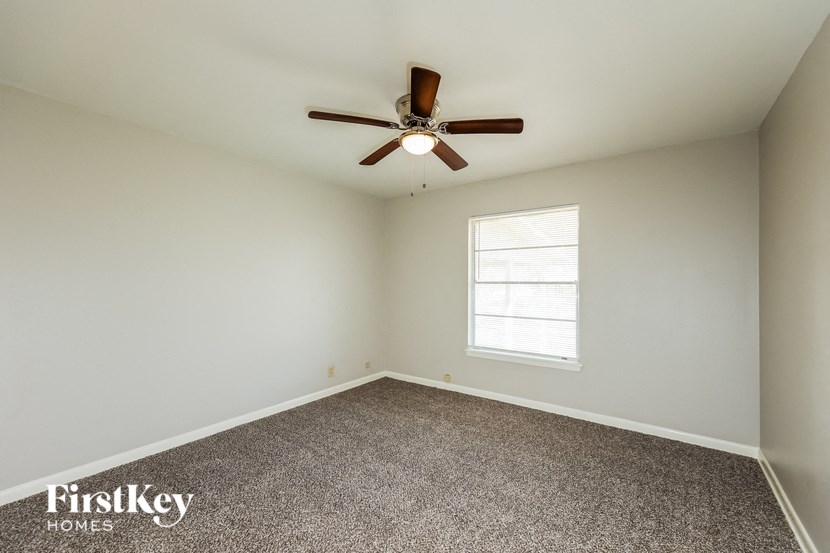 an empty room with a ceiling fan and a window