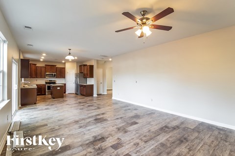 A spacious living room with a wood floor and a ceiling fan.