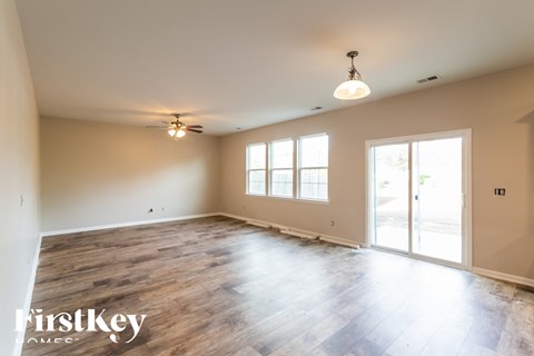 A spacious room with wooden flooring and a ceiling fan.